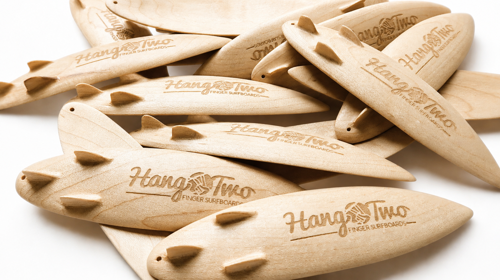 A pile of light natural wood finger surfboards engraved with the brand name 'Hang Two'.
