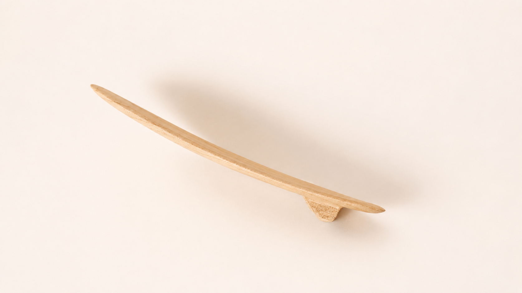 A light natural wooden finger surfboard with two fins, viewed from the side, displaying the board's curvature - ideal for catching the breeze.